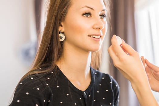 Young beautiful girl applying make-up by make-up artist