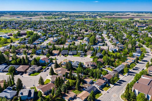 Experience the serene beauty of Lakeridge in Saskatoon from above. This drone image showcases the neighborhood's tranquil streets, lush green spaces, and the harmonious blend of urban and nature.