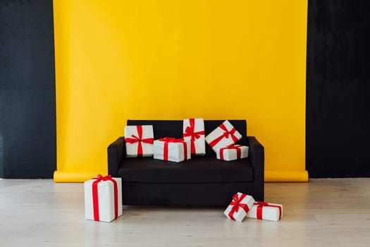 black sofa with feasting gifts in the interior of the room with a yellow background