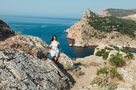 Beautiful woman in dress looks at the ocean view from the cliff