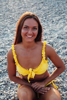 tanned woman in yellow swimsuit sunbathes on the beach