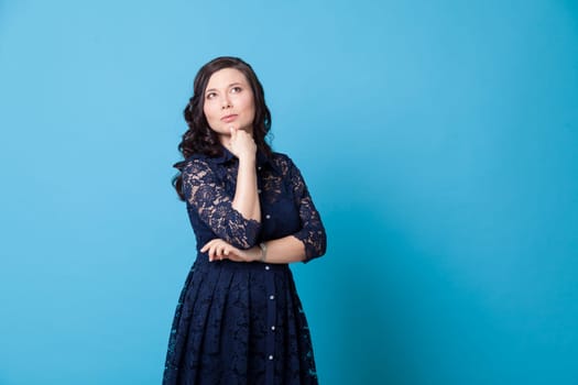 Portrait of a beautiful Asian woman in a blue dress holds her chin with her hand