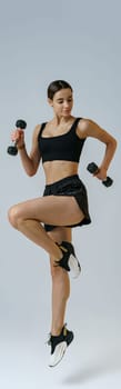 Woman doing cardio exercises with dumbbells on studio background . Healthy lifestyle