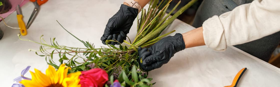 Female decorator creating beautiful bouquet at table. Lifestyle flower shop