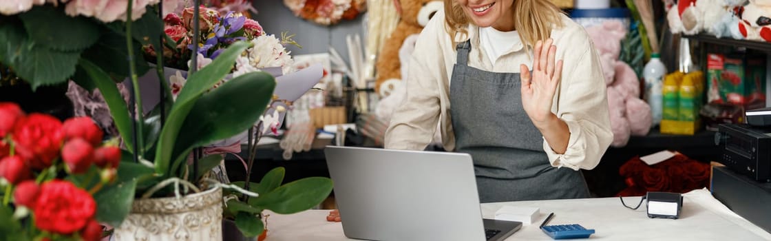 Woman florist talking via video call during working day in floral shop. High quality photo
