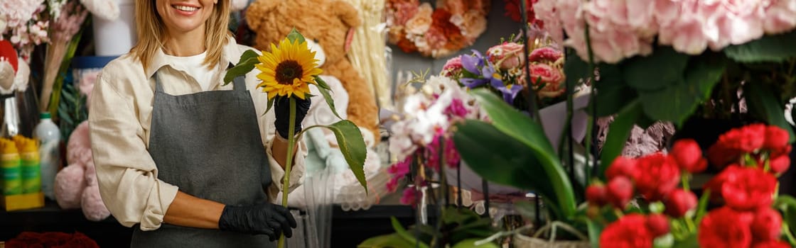 Female decorator creating beautiful bouquet at table. Lifestyle flower shop