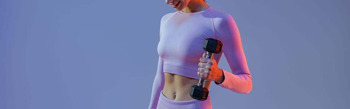 Woman doing exercises with dumbbells on studio background . Sport and healthy lifestyle