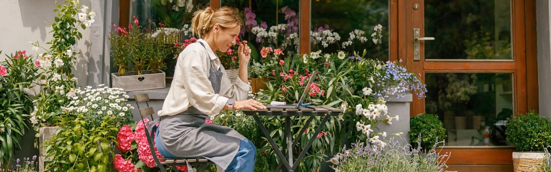 Smiling flower shop owner working on laptop computer. Occupation working concept