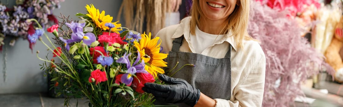 Woman florist smiling and holding beautiful flowers composition in flower shop ready to sale