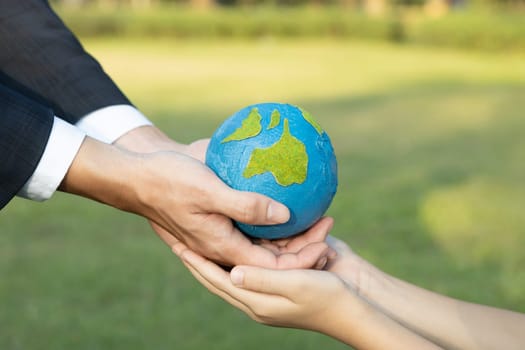 Businessman hand giving Earth globe to little boy as Earth day concept as corporate social responsible to contribute greener environmental protection for sustainable future generation. Gyre