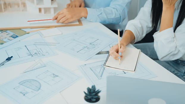 Professional engineer measures house model while skilled designer writes down in blueprint. Work together, collaboration, cooperate. Creative design and team working concept. Closeup. Immaculate