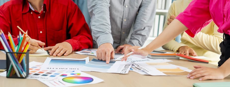 A cropped image of professional interior designer discuss the color material with her colleagues by comparing with color swatches and color palette document. Creative design concept. Variegated.