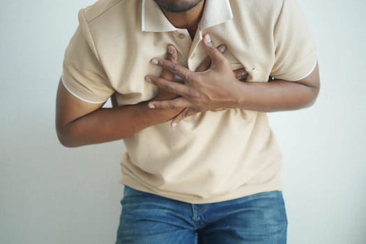 young man suffering pain in heart and holding chest with hand .