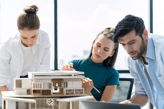 Portrait of skilled architect holding laptop while present idea to engineer team. Group of businesspeople brainstorm and analysis building construction. Civil engineering, working together. Tracery.