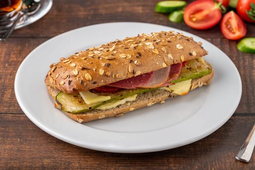 Vegetable and ham sandwich with tea on wooden table