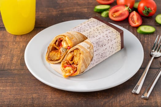 Chicken wrap with vegetables on a white porcelain plate on wooden table