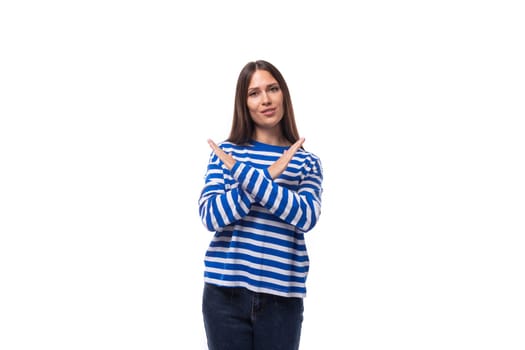 young charming brunette lady with straight hair dressed in a blue sweater crossed her arms on a white background with copy space.