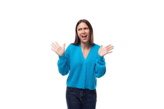 young confused caucasian woman with black hair dressed in a blue cardigan and jeans thought on a white background.