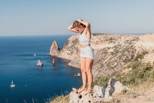 Woman travel sea. Young Happy woman in a long red dress posing on a beach near the sea on background of volcanic rocks, like in Iceland, sharing travel adventure journey