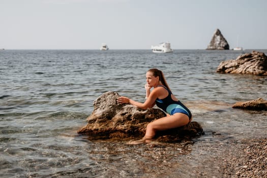 Woman travel sea. Young Happy woman in a long red dress posing on a beach near the sea on background of volcanic rocks, like in Iceland, sharing travel adventure journey