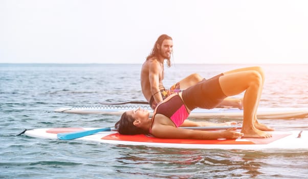 Woman sup yoga. Happy young sporty woman practising yoga pilates on paddle sup surfboard. Female stretching doing workout on sea water. Modern individual female outdoor summer sport activity