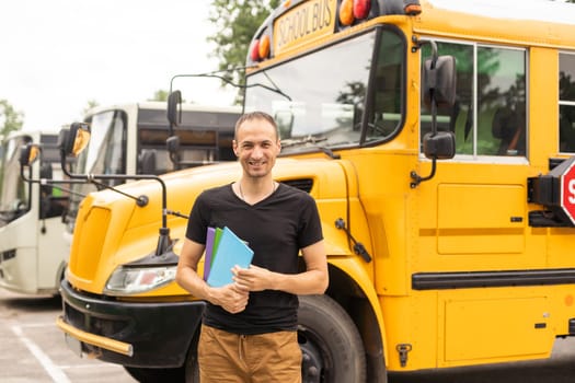 Portrait of young teacher near the school bus.