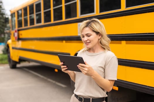 Portrait of cheerful teacher standing near the school bus