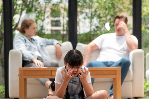 Stressed and unhappy young girl crying and trapped in middle of tension by her parent argument in living room. Unhealthy domestic lifestyle and traumatic childhood develop to depression. Synchronos