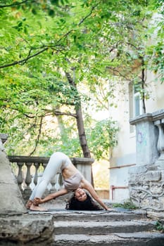 Young brunette woman practicing yoga during workout in park