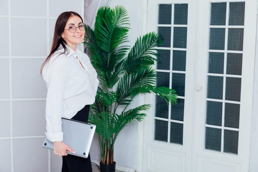 female gardener in glasses using laptop, communicates on internet with customer in home