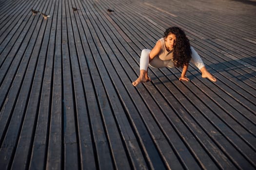 Young woman doing yoga exercises in the autumn city park.