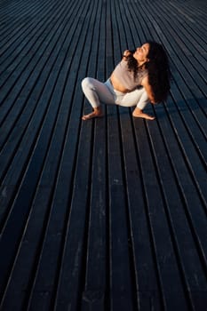 Young woman doing yoga exercises in the autumn city park.