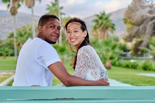 Outdoor portrait of multiracial couple embracing together, nature exotic park background, copy space. Multicultural family, Asian woman and African American man. Relationships lifestyle people concept