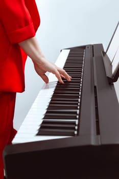 The girl plays the piano with one hand. Pianist's hand on the keys close-up. Partial focus