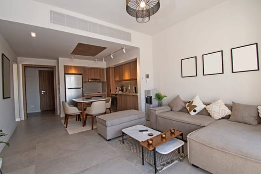 Living room lounge area in luxury tropical holiday apartment show home showing interior design decor furnishing with open plan kitchen design