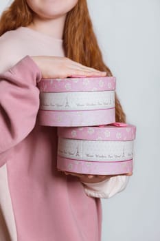 A girl with red hair holds gift boxes in her hands