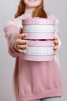 A girl with red hair holds out gift boxes