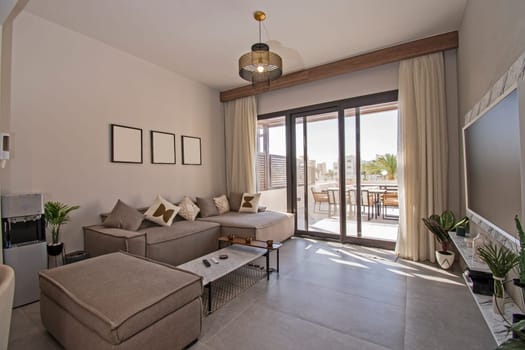 Living room lounge area in luxury tropical holiday apartment show home showing interior design decor furnishing with open plan design and large balcony terrace