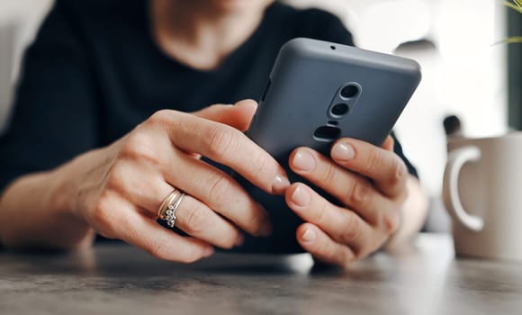 Young Woman Using A Smartphone Surfing On The Internet And Smiling In The Kitchen