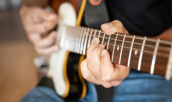 Man hand playing on electric guitar closeup. Musician performing live with acoustic string instrument with fretboard