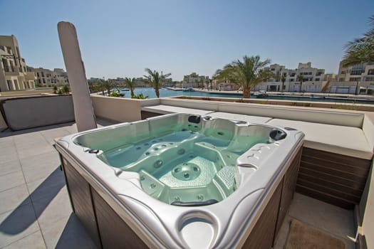 Roof terrace patio furniture at a luxury holiday villa in tropical resort with hot tub and marina view
