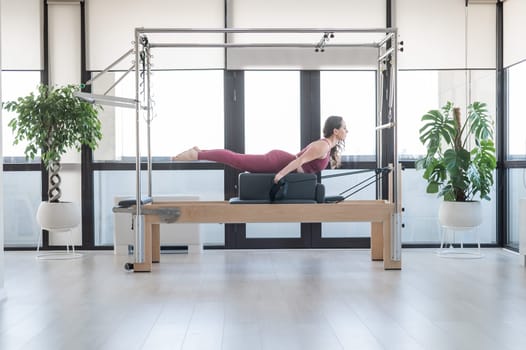 Woman doing pilates exercise on cadillac reformer machine