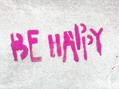 Pink Be happy written in graffiti style with rough texture isolated on gray background.