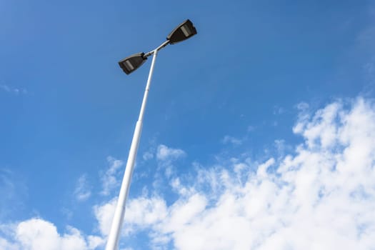 LED lantern for street lighting. Modern street lamp on a metal pole against the blue sky with white clouds. Modern LED lamp street lighting.