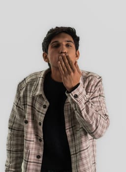 Young handsome man blowing kisses to the camera, looking at it with hand on his mouth