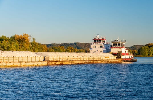 Large grain shipment on Upper Mississippi in barge being pushed by two large pusher tugs on river