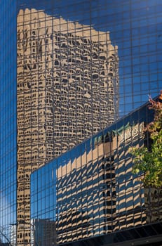 Reflections of two modern office skyscrapers in a mirrored building on Market street in downtown St Louis in Missouri