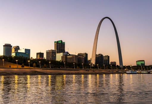 St Louis, MO - October 21, 2023: Low water levels in Mississippi river with reflections of the Gateway arch towering over the riverbank at dusk