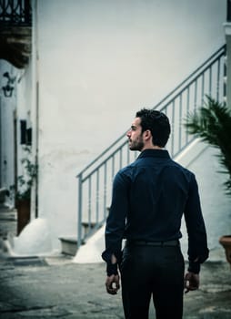 A man standing in front of a set of stairs. The Majestic Staircase: A Man's Solemn Pose at the Foot of a Grand, Ascending Path, seen from behind