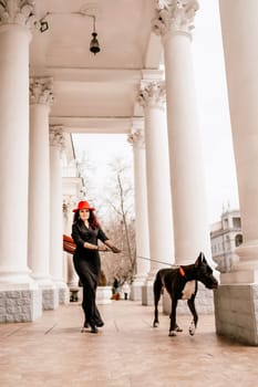 A photo of a woman and her Great Dane walking through a town, taking in the sights and sounds of the urban environment.